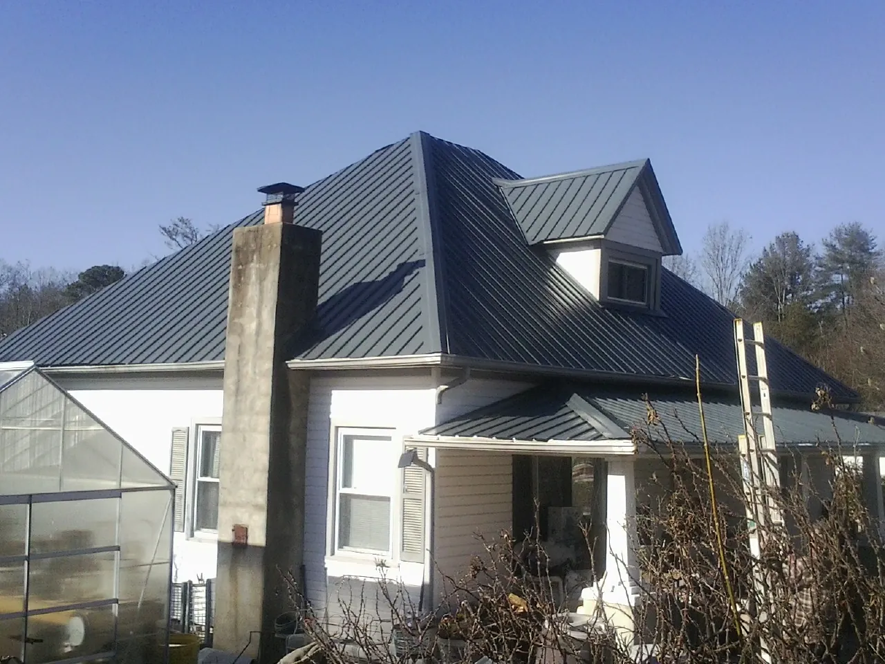 Dark blue standing seam metal roof on a white farmhouse with dormer — Slate & Tile Roof Repair by Roofing Brothers in Elgin