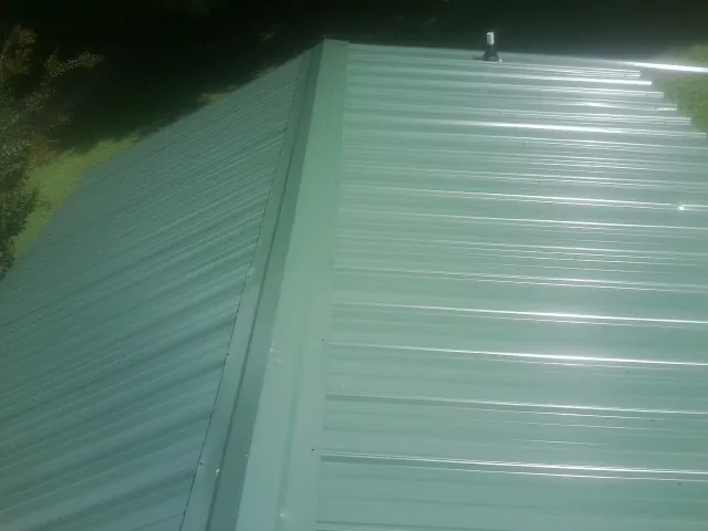 New green metal panels meeting at the ridge of a roof — Flat Roof Repair work by our crew in Elgin